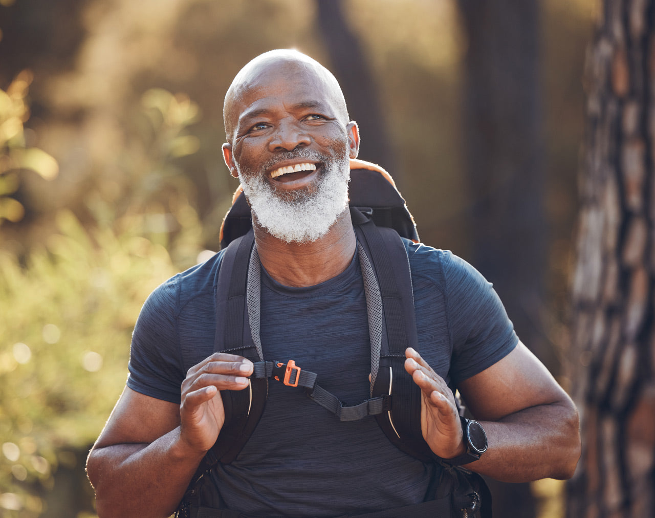 man walking outdoors with backpack on and smiling - Greskas c60 carbon 60 supplement